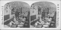 SA0444 - Photo shows tables set for eating, chairs, paper garlands hanging from ceiling, etc. Identified on the back. Contains ads for other views in the series on the back.